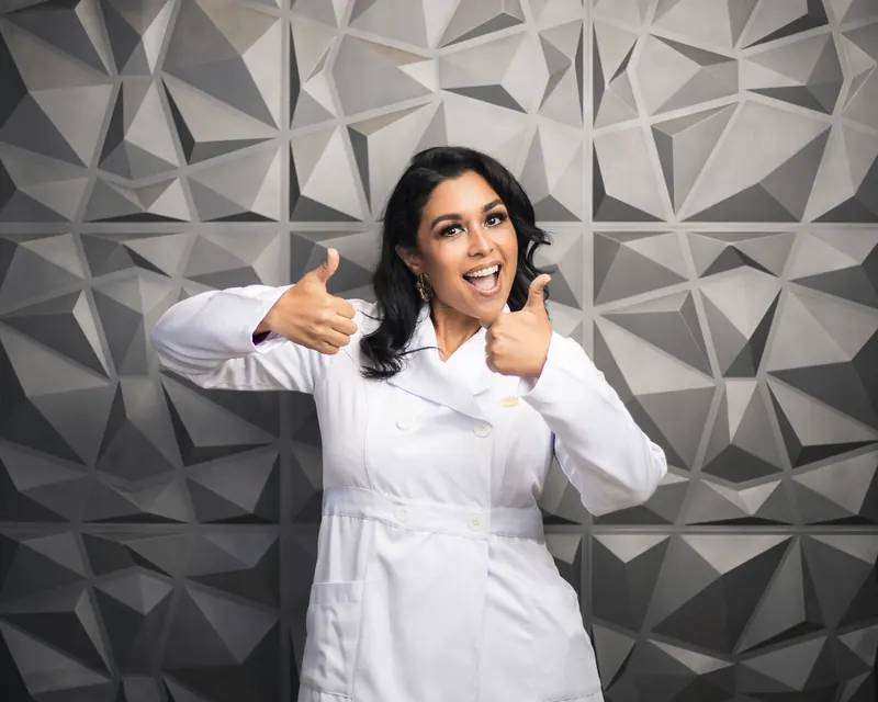 Dra. Mónica Tribaldos sonriendo con los pulgares arriba en su consultorio